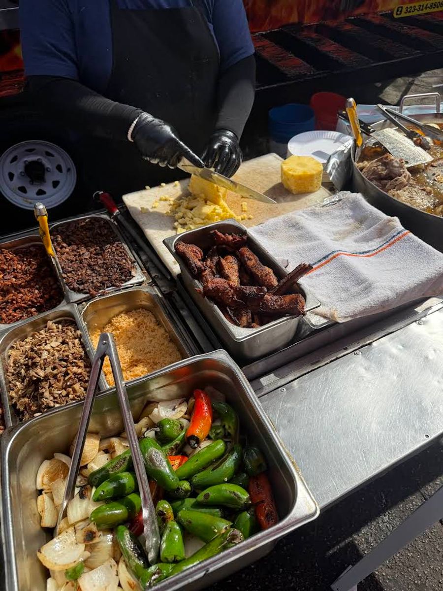 Hands preparing tacos at Tacos Los De La Esquina